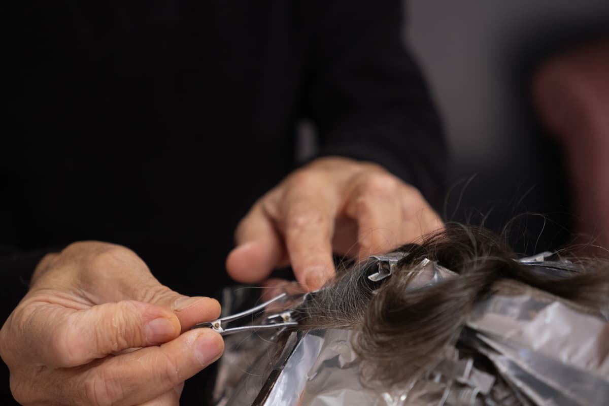 Hairdresser coloring a client's hair with a brush and foil